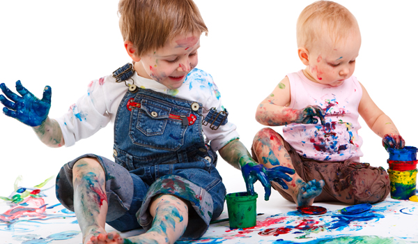 Cute 5 years old boy and toddler girl painting on white background