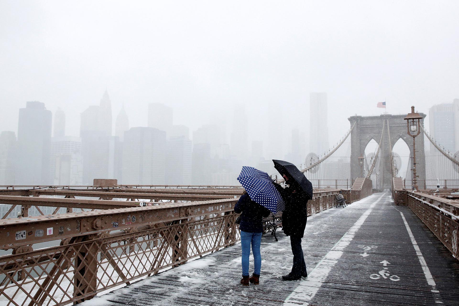 People look out on lower Manhattan from the Brooklyn Bridge during a snow storm in New York City, U.S. March 14, 2017. REUTERS/Brendan McDermid