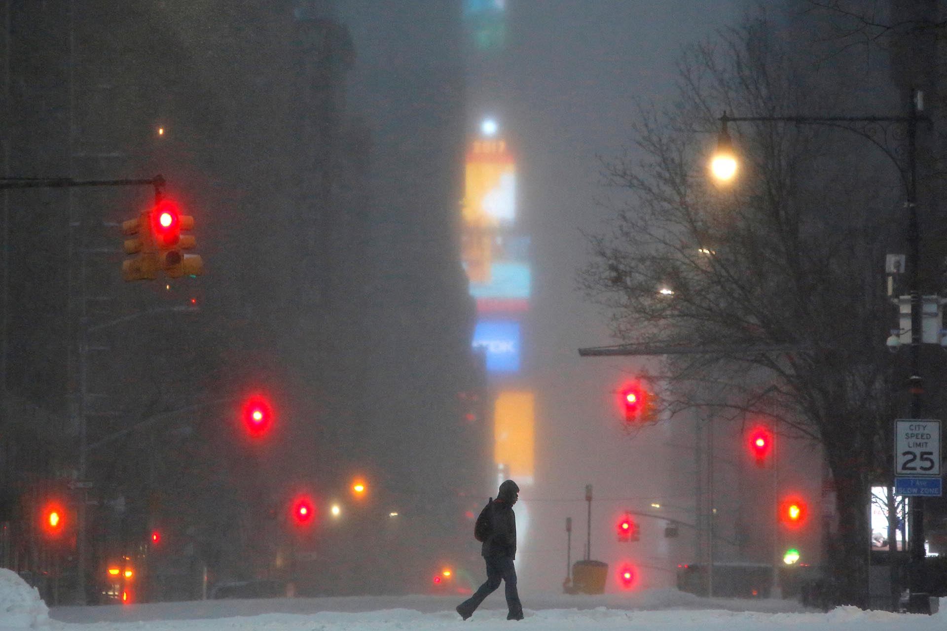 Times Square is seen in the background as a man walks along West 59th street in falling snow in Manhattan, New York, U.S., March 14, 2017. REUTERS/Andrew Kelly TPX IMAGES OF THE DAY