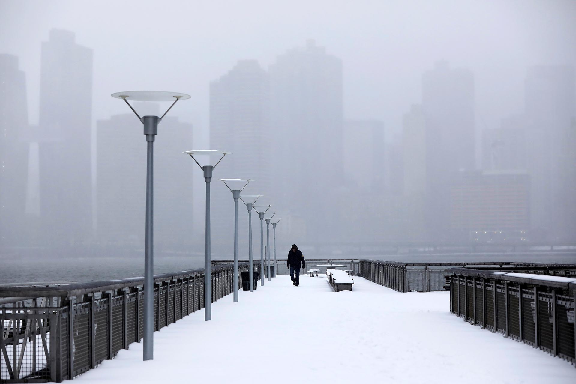 A man walks along the Harlem river waterfront during snowy conditions in the Queens borough of New York, U.S., March 14, 2017. REUTERS/Shannon Stapleton