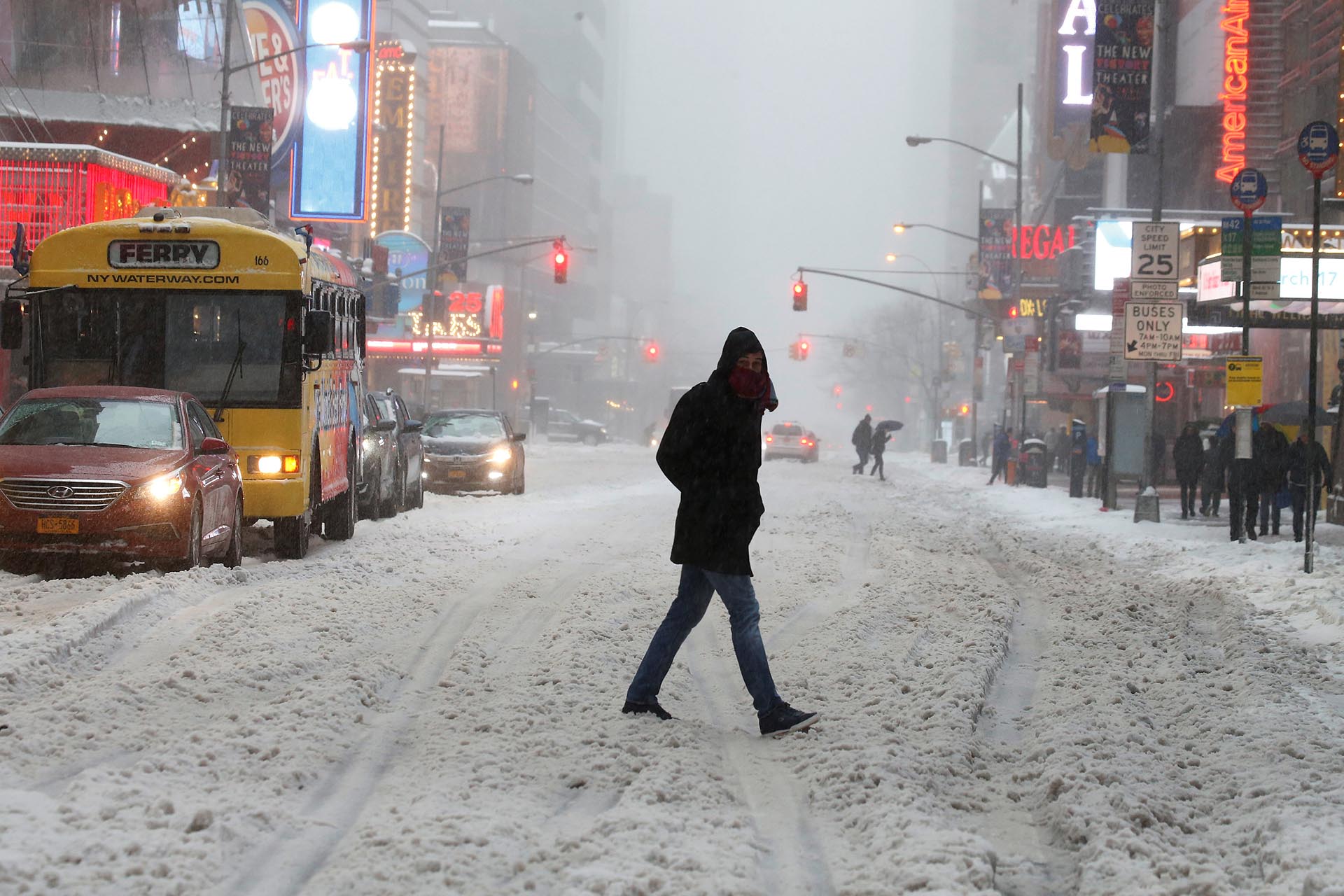 A commuter walks across a street during a snowstorm in Times Square in the Manhattan borough of New York, New York, U.S. March 14, 2017. REUTERS/Carlo Allegri