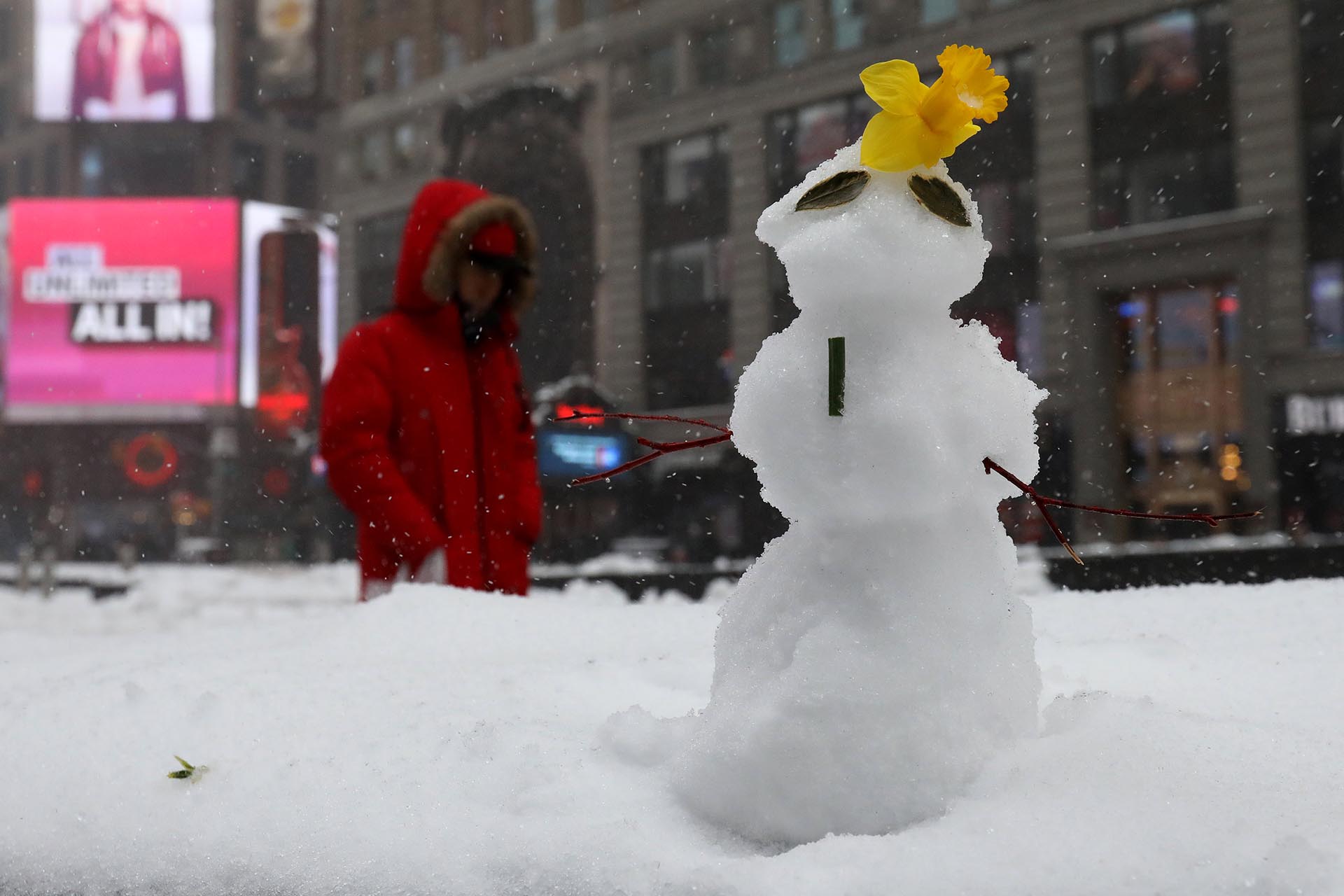 A person walks with an umbrella past a snowman during a snow storm in Times Square in the Manhattan borough of New York, New York, U.S. March 14, 2017. REUTERS/Carlo Allegri